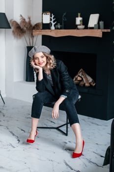 A girl in a beret and red shoes is sitting on a table in the interior photo