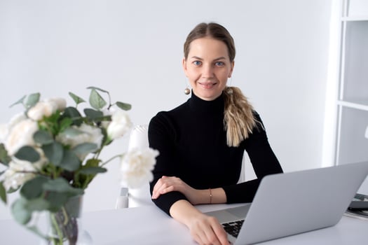 The girl works in a white office with a laptop and flowers on the table photo