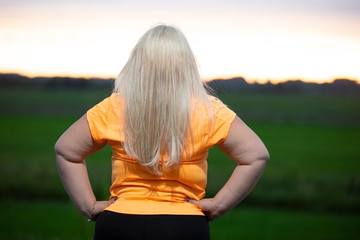 Chubby blonde woman stands with her back to the camera and rests after sports. photo