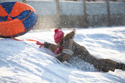 A happy boy up in the air on a tube sledding in the snow.. A boy slides down a hill in winter. photo