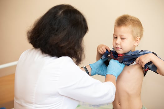The doctor uses a stethoscope on the boy's stomach to check his health. photo