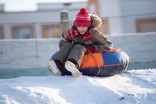 A happy boy up in the air on a tube sledding in the snow.. A boy slides down a hill in winter. photo
