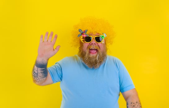 Fat man with wig in head and sunglasses greets with his hand photo