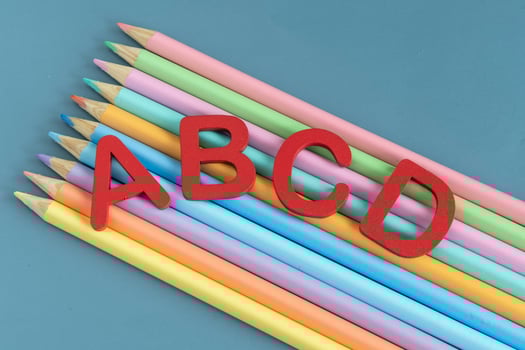 Back to school concept with assorted letters and colored pencils in pastel colors photo