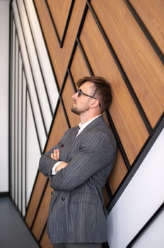 a young man in a suit and sunglasses is standing in a room near the wall photo