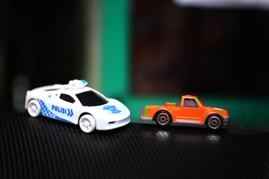 Concept photo of a toy police car chasing an orange car