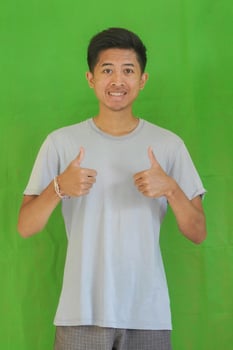 expressive casual Balinese Asian guy model for advertising with green screen studio background photo
