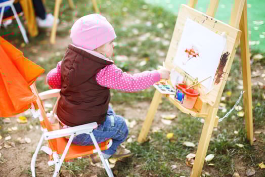 little girl draws  on the easel. the child paints photo