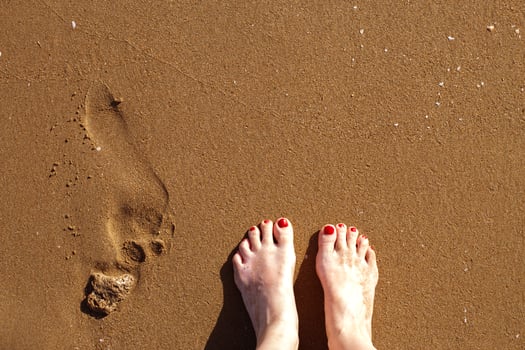 a human footsteps and female feet on a sandy beach photo