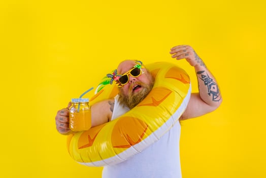 Fat annoyed man with wig in head is ready to swim with a donut lifesaver photo
