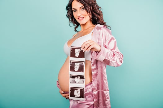 Pregnant mom shows an ultrasound of her happy son photo