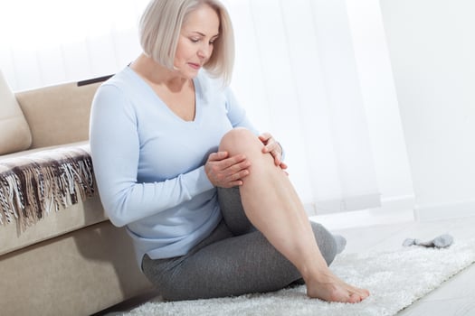 Middle-aged woman suffering from pain in leg at home, closeup. Physical injury concept. photo