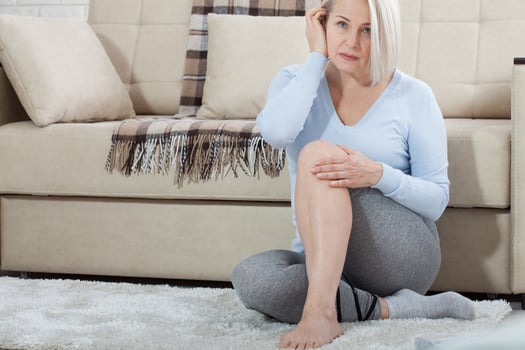 Middle-aged woman suffering from pain in leg at home, closeup. Physical injury concept. photo