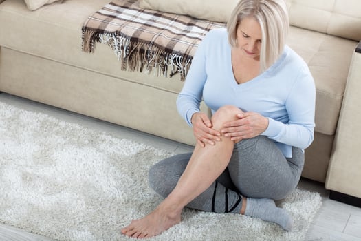 Middle-aged woman suffering from pain in leg at home, closeup. Physical injury concept. photo