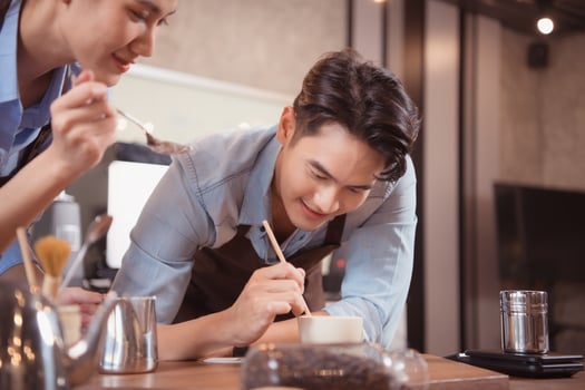 Before competing in the championship level coffee brewing competition, both of the baristas practice their coffee latte makeup techniques to become proficient. photo