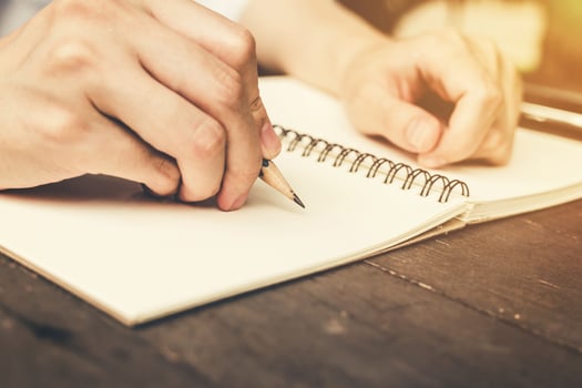 close up hand woman writing notebook with pencil on wood table. Vintage toned filter. photo