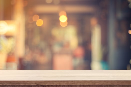 Empty wooden table for product placement or montage and blurred coffee shop backdrop. photo