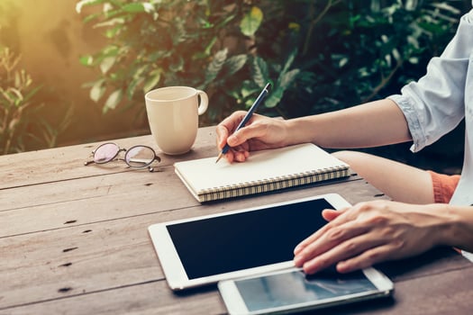 Woman hand writing note pad on wood table in coffee shop. photo
