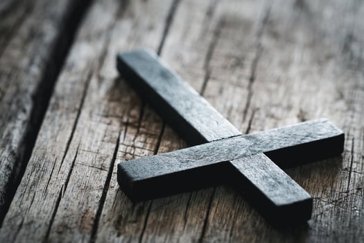 A wooden Christian cross crucifix on a grunge board background. Wooden Christian cross on grey table against blurred lights, space for text. photo