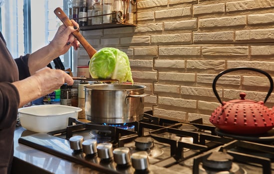 Chef takes boiled Cabbage out of the pot on the gas stove photo