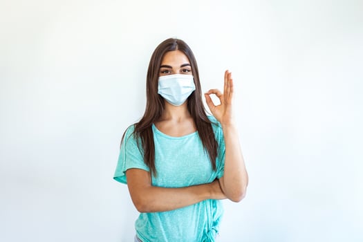 Woman with a medical disposable mask to avoid contagious viruses, Showing OK sign. Corona virus prevention. Concept of coronavirus quarantine. Attention photo