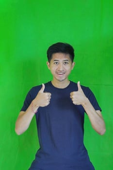 expressive casual Balinese Asian guy model for advertising with green screen studio background photo