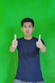 expressive casual Balinese Asian guy model for advertising with green screen studio background photo