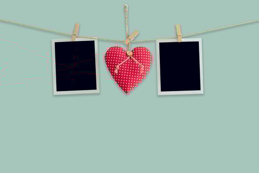 Blank instant photos and red heart hanging pastel color background.
