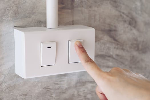 Women hand turn on lights electric switch on cement wall background photo