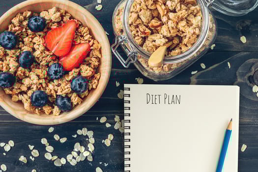 Homemade granola and fresh berries on wood table with note book and text diet plan concept, copy space. photo