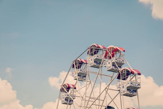 Ferris wheel on cloudy sky background with vintage toned. photo