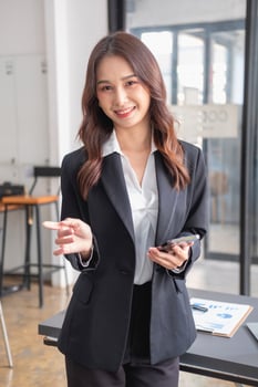 Marketing, Financial, Accounting, Planning, bAsian female entrepreneur in hand holding a smart phone Expressing joy that the company has succeeded in gaining profits from business management. photo
