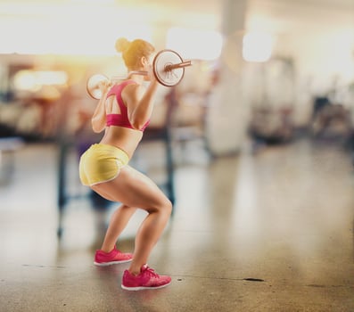 Athletic girl works out at the gym with a barbell photo