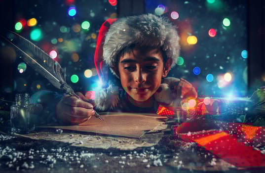 Child with Christmas hat writes a letter to santa claus for gifts photo