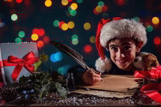 Child with Christmas hat writes a letter to santa claus for gifts photo