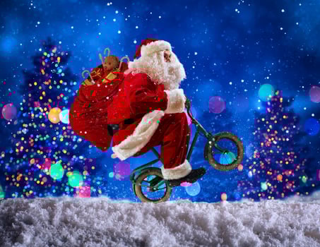 Santaclaus wheelie with bike to deliver fast christmas gifts photo