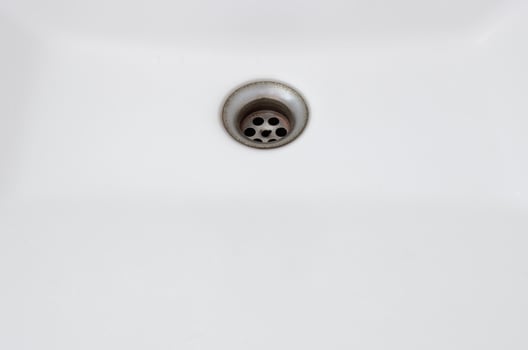 The rusty sinkhole in the white basin of the public toilet. photo