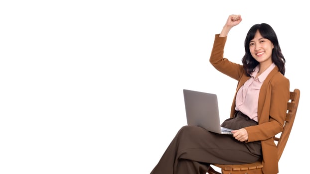 Happy young business asian woman celebrating on her success. While her using laptop sitting on wooden chair isolate on white background photo