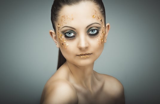 Glamorous portrait of young beautiful girl with big blue eyes, lush lashes and bright golden makeup photo