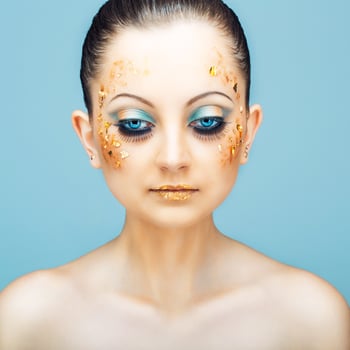 Glamorous portrait of young beautiful girl with big blue eyes, lush lashes and bright golden makeup. Fashion shiny highlighter on skin, velvet skin, gold lipsGlamorous portrait of young beautiful girl with big blue eyes, lush lashes and bright golden make photo