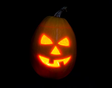 Halloween pumpkin jack-o-lantern candle lit, isolated on black photo