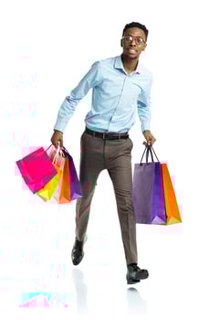 Happy african american man holding shopping bags on white background photo