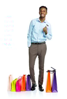 Happy african american man with shopping bags and holding credit card on white background photo