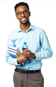 Happy african american college student with books and bottle of water in his hands standing on white photo