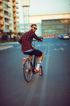 Man in sunglasses riding a bike on city street photo