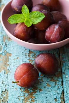 Bowl with plums on blue shabby wooden background photo