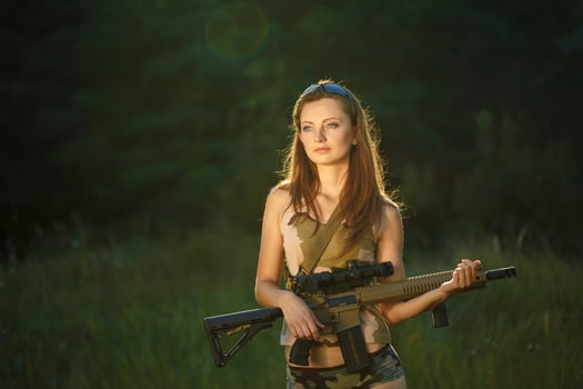 Young beautiful girl with a shotgun in an outdoor photo