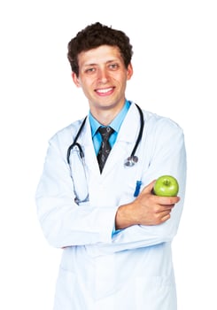 Portrait of a smiling male doctor holding green apple on white photo
