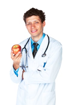 Portrait of a smiling male doctor holding red apple on white photo