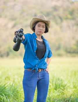 Woman wear hat and hold binocular in grass field photo